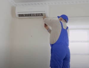 man servicing ac unit on wall
